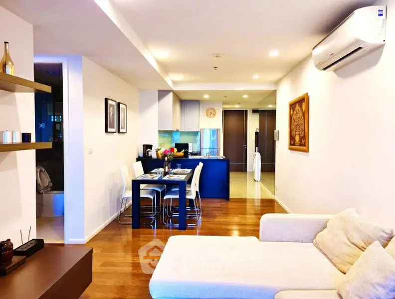 Modern open-plan living room with dining area and kitchen, featuring stylish decor and wooden flooring.