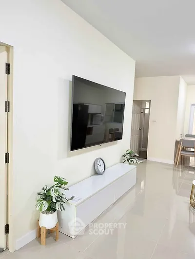 Modern living room with wall-mounted TV and sleek white furniture, perfect for contemporary living.