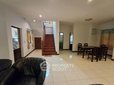 Spacious living room with elegant staircase and dining area in modern home.
