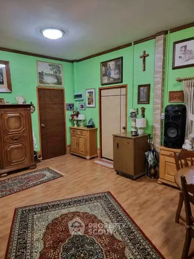 Charming living room with wooden furniture and vibrant green walls, featuring elegant decor and cozy ambiance.