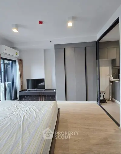 Modern bedroom with sliding glass door to kitchen, featuring sleek design and ample natural light.