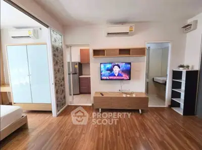 Modern living room with wooden flooring, wall-mounted TV, and air conditioning in a stylish apartment.