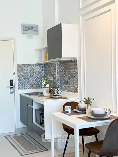 Charming compact kitchen with stylish backsplash and cozy dining area in modern apartment.