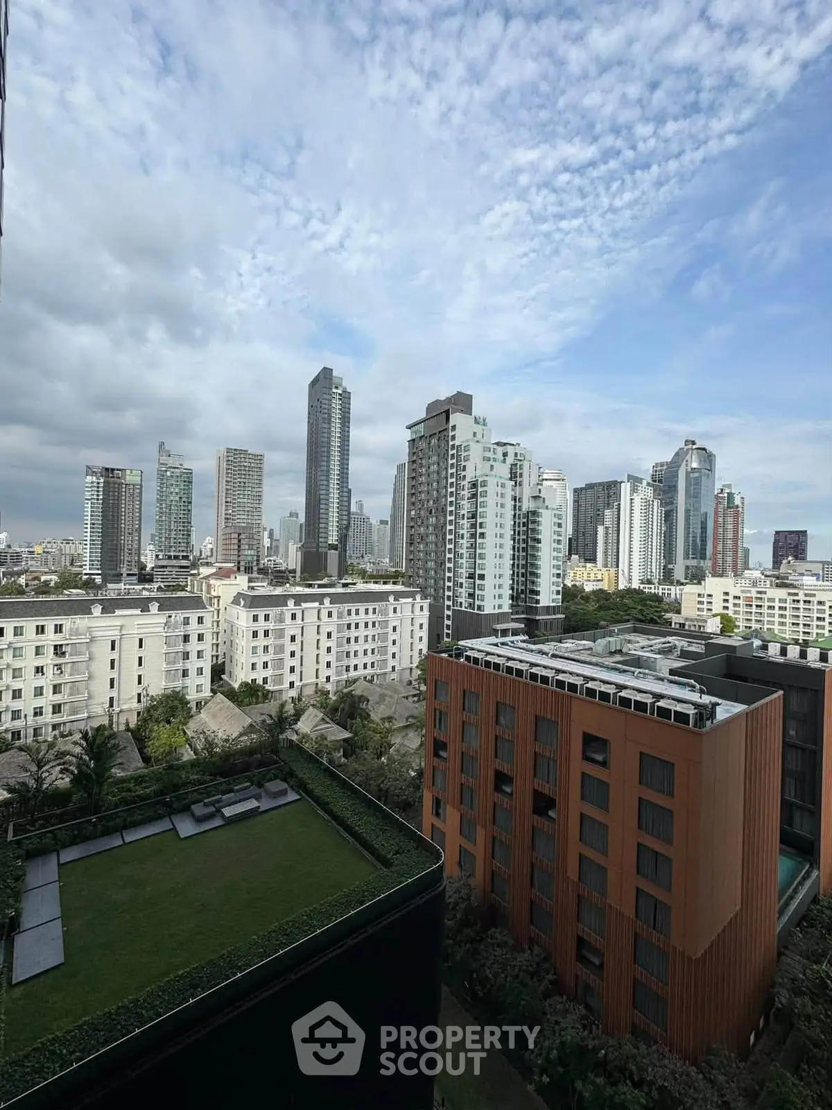 Stunning cityscape view from a high-rise building showcasing modern architecture and lush greenery.