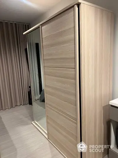 Sleek modern bedroom with a large mirrored wardrobe reflecting a tastefully decorated space, enhancing the room's brightness and sense of space.