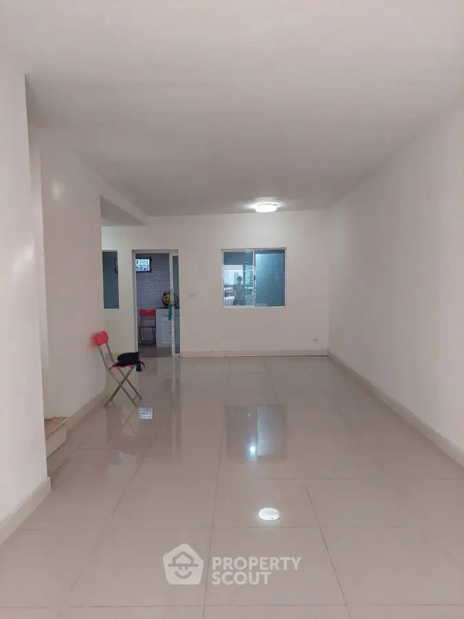 Spacious empty living room with tiled flooring and minimalistic design.