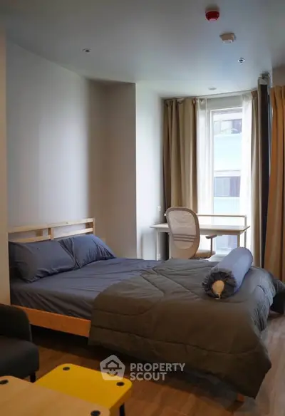Modern bedroom with cozy bed and study desk near window, perfect for urban living.