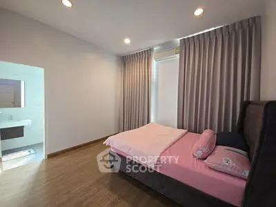 Cozy bedroom with elegant curtains and soft lighting, featuring a comfortable bed and wooden flooring.