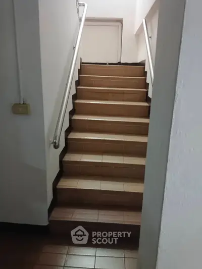 Staircase with brown tiles and metal handrails in a residential building.
