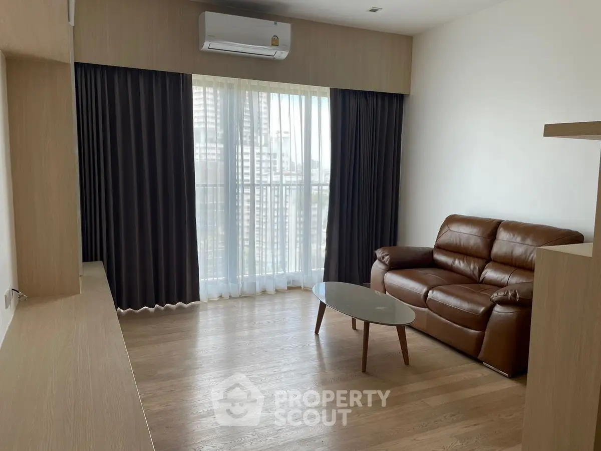 Modern living room with leather sofa and large window in a stylish apartment.