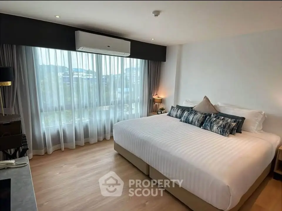 Spacious bedroom with large window and modern decor in a luxury apartment.