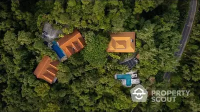 Aerial view of luxurious villas with pools nestled in lush greenery, offering a serene and private retreat.