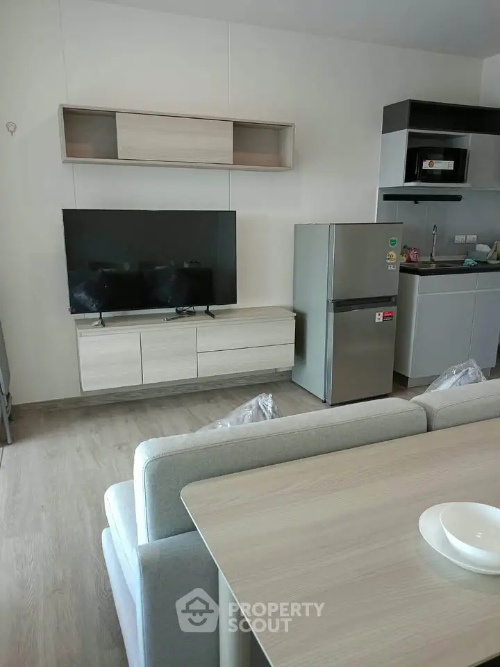 Modern living room with sleek furniture and kitchen appliances in a stylish apartment.