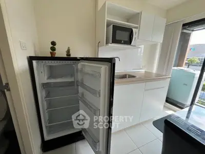 Modern kitchen with open fridge and microwave, bright natural light