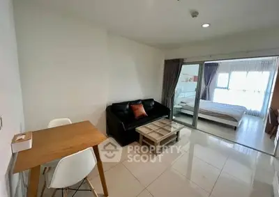 Modern open-plan living room with cozy seating and adjacent bedroom view.
