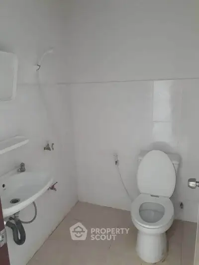 Minimalist bathroom with white tiles and basic fixtures, ideal for compact spaces.