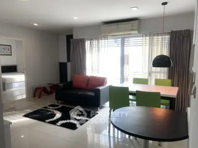 Modern living room with sleek furniture and natural light, featuring a stylish dining area and air conditioning.