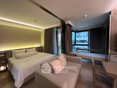Modern bedroom with cozy seating area and large windows offering natural light