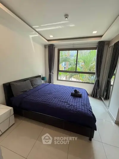 Modern bedroom with large window and stylish decor, perfect for relaxation.