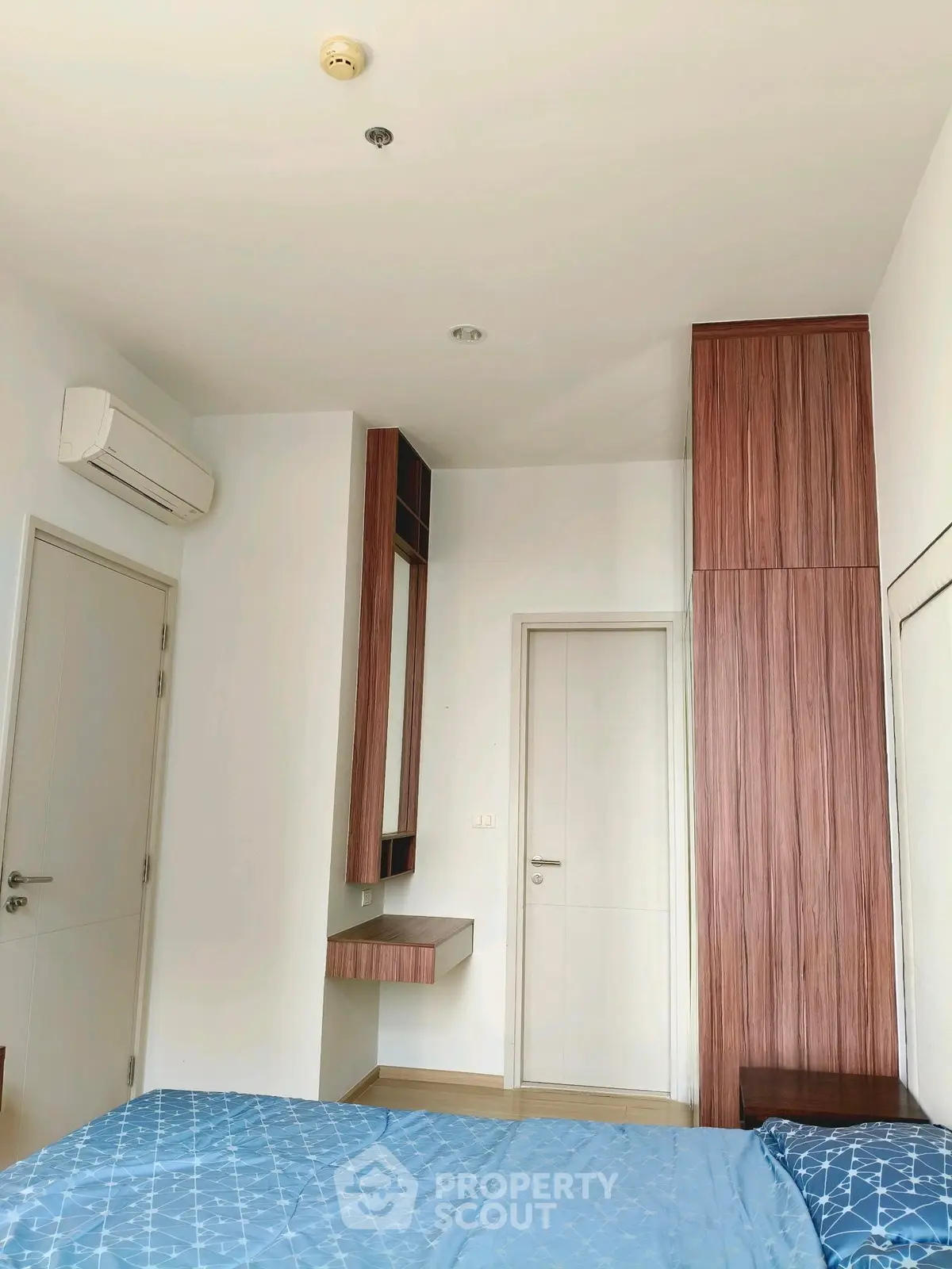 Modern bedroom with sleek wooden cabinetry and blue bedding