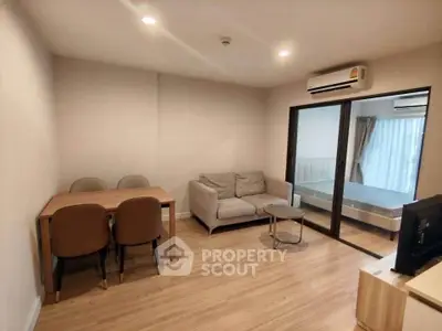 Modern living room with dining area and view into bedroom, featuring sleek furniture and wooden flooring.