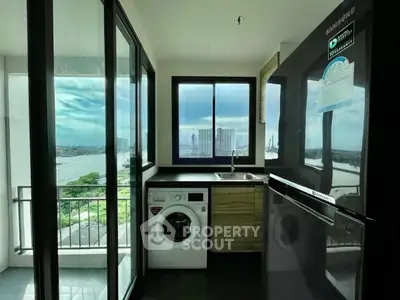 Modern kitchen with washing machine and stunning river view from balcony.