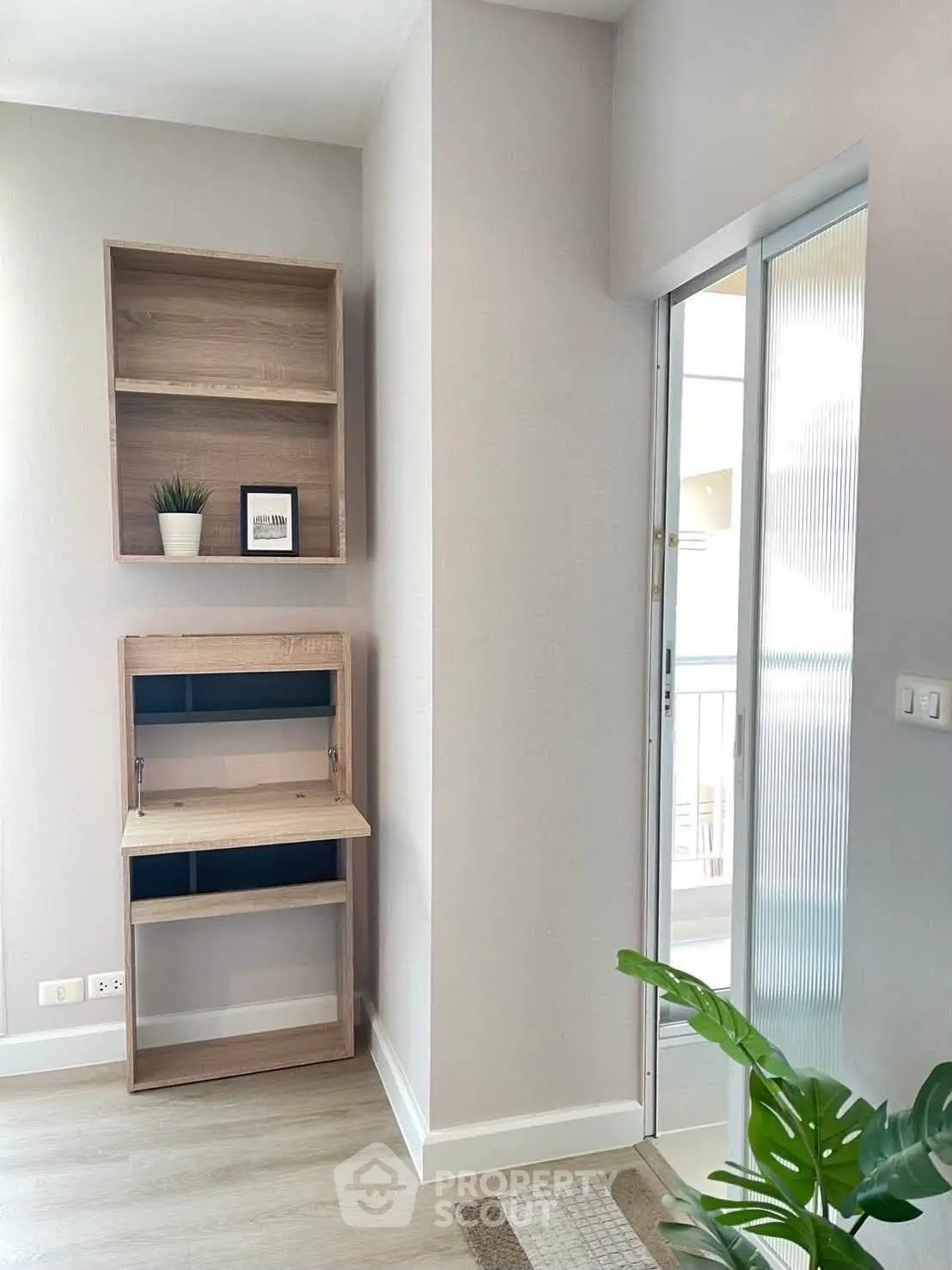 Modern study nook with wooden shelves and desk, adjacent to a bright balcony area.