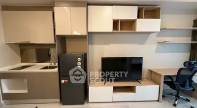 Modern apartment interior with sleek kitchen and cozy living area featuring TV and desk.