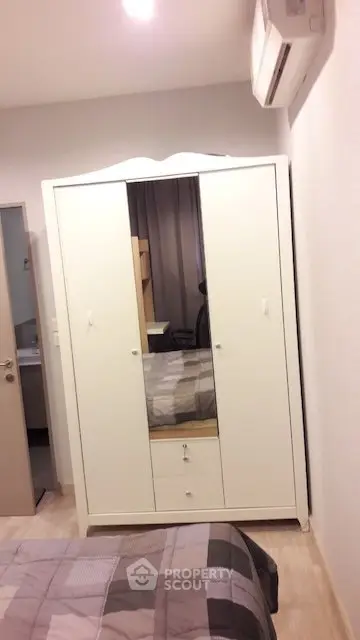 Cozy bedroom with white wardrobe and air conditioning, perfect for comfortable living.