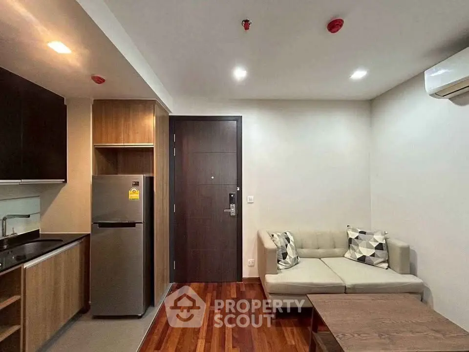 Modern apartment interior with cozy living room and compact kitchen featuring sleek appliances.