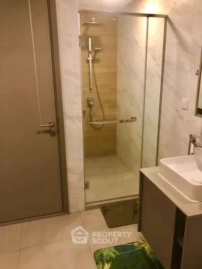 Modern bathroom with glass shower enclosure and sleek vanity in contemporary apartment.