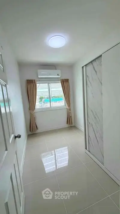 Bright and modern small bedroom with air conditioning and large window.