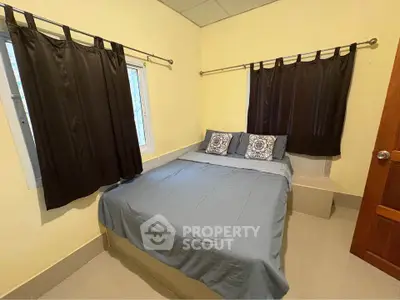 Cozy bedroom with double bed and dark curtains, perfect for restful nights.