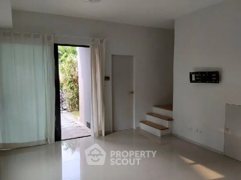Spacious modern living room with open access to garden, featuring sleek design and natural light.