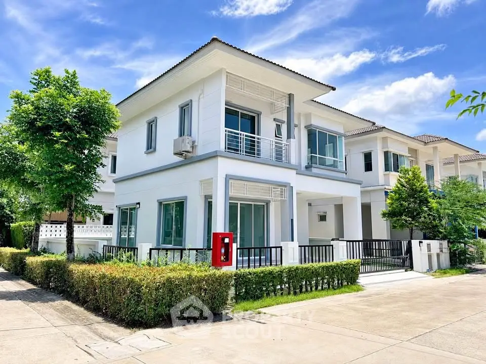 Modern two-story white house with lush greenery and clear blue sky, perfect suburban living.
