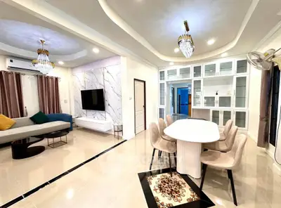 Luxurious open-plan living and dining area with elegant chandeliers and modern decor.
