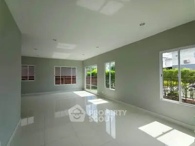 Spacious sunlit living room with large windows and modern tile flooring, perfect for family gatherings.