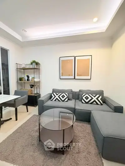 Modern living room with stylish gray sofa, glass coffee table, and chic decor accents.