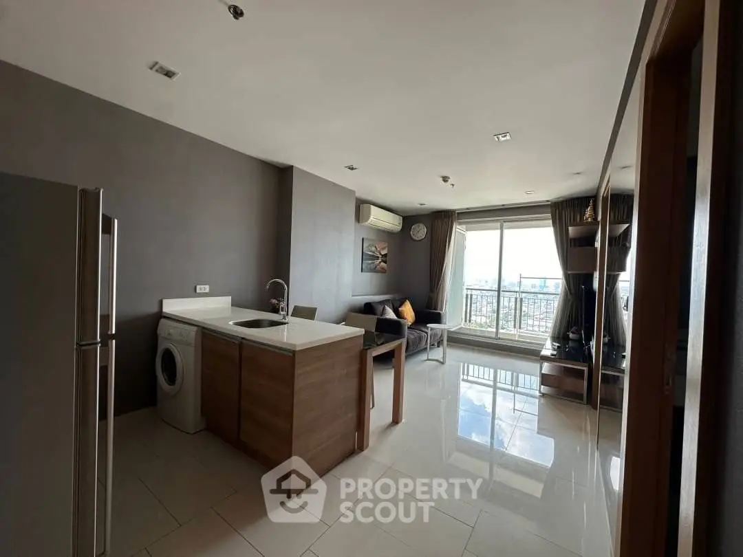 Modern open-plan living room with kitchen and city view, featuring sleek design and natural light.