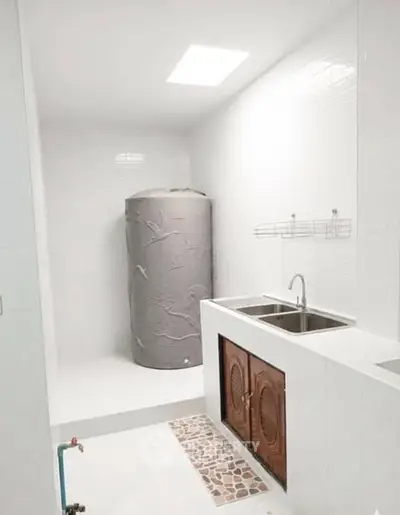 Spacious utility room with dual sink and water heater, ideal for efficient home management.