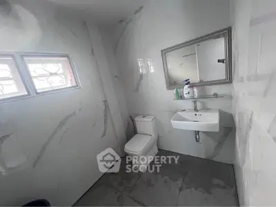 Modern bathroom with sleek design, featuring a toilet, sink, and large mirror.