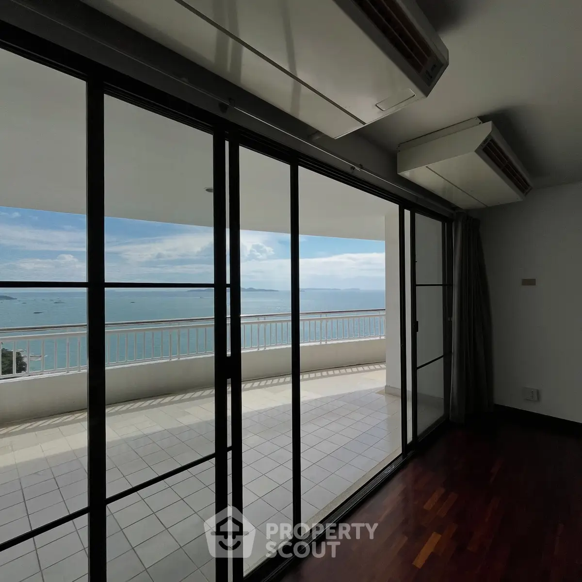 Stunning ocean view from modern apartment with spacious balcony and floor-to-ceiling windows.