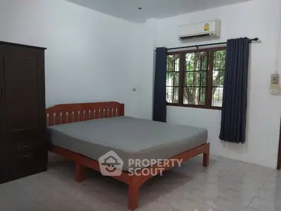 Cozy bedroom with wooden bed frame and air conditioning, perfect for restful nights.