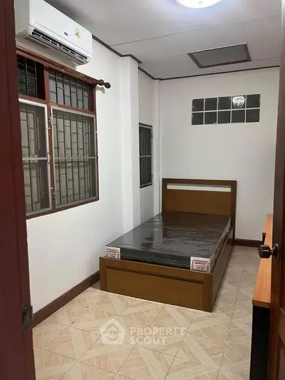 Cozy bedroom with wooden bed frame and air conditioning, perfect for a comfortable living experience.