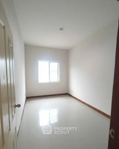 Spacious empty bedroom with large window and glossy floor, perfect for customization.