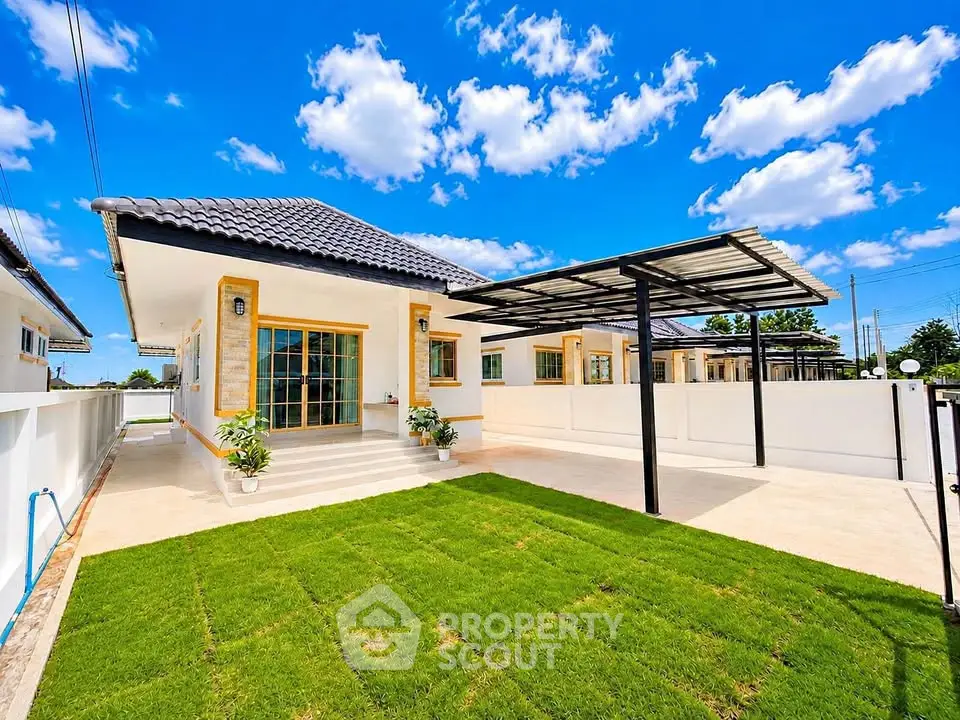 Charming single-story home with spacious driveway and lush green lawn under a bright blue sky.