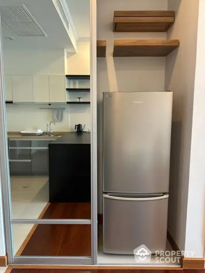 Modern kitchen with sleek fridge and open shelving in stylish apartment.