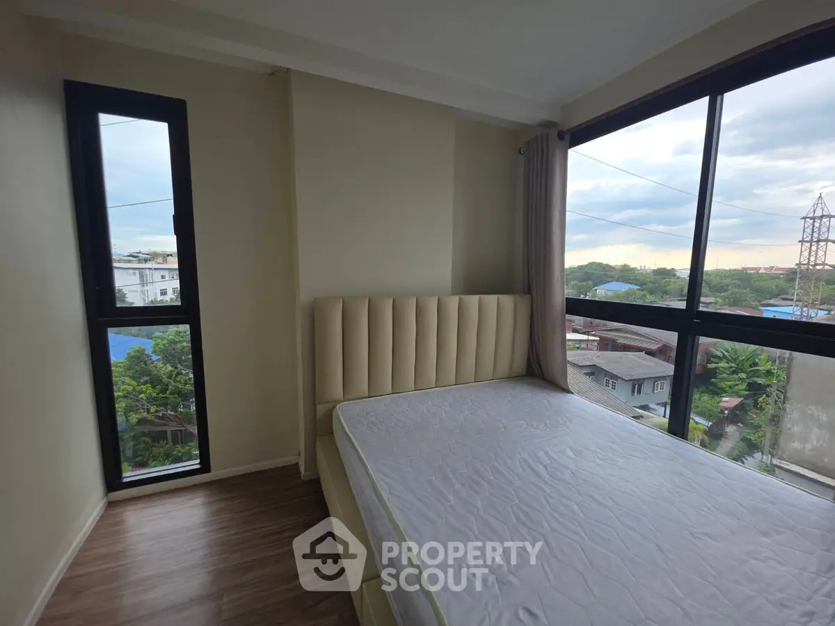 Bright bedroom with large windows offering a stunning view, featuring a modern bed and elegant flooring.