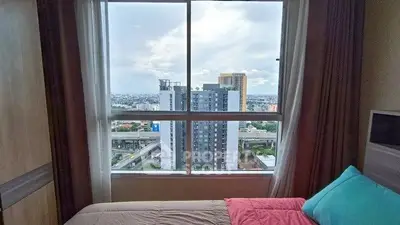 Cozy bedroom with city view from large window, perfect for urban living.
