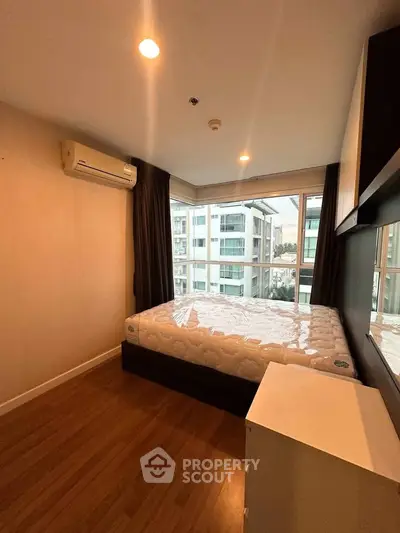 Modern bedroom with large windows and city view, featuring a comfortable bed and air conditioning.